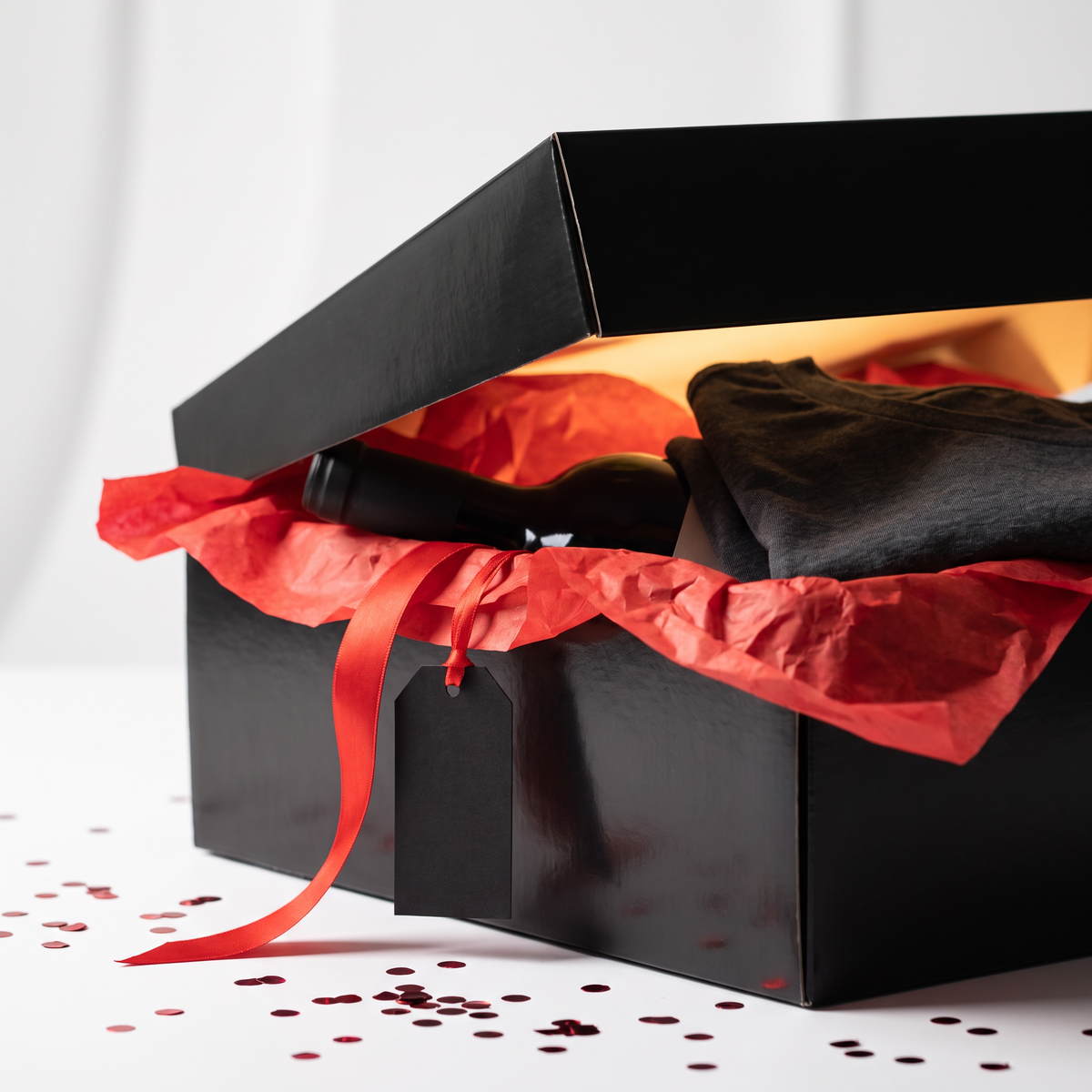 Love Cork Screw Mystery Sip Box, a black gift box with red tissue paper and a surprise tee and bottle of wine inside