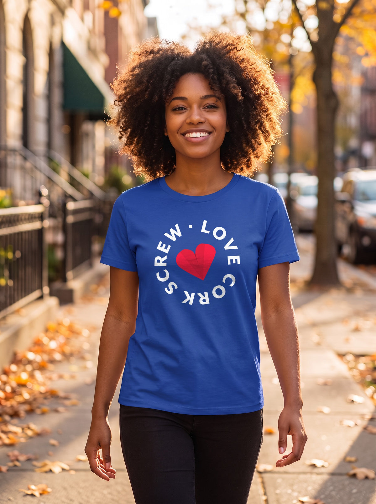 Woman walking down an autumn city street in the royal blue Cork Blue tee with the Love Cork Screw circle logo