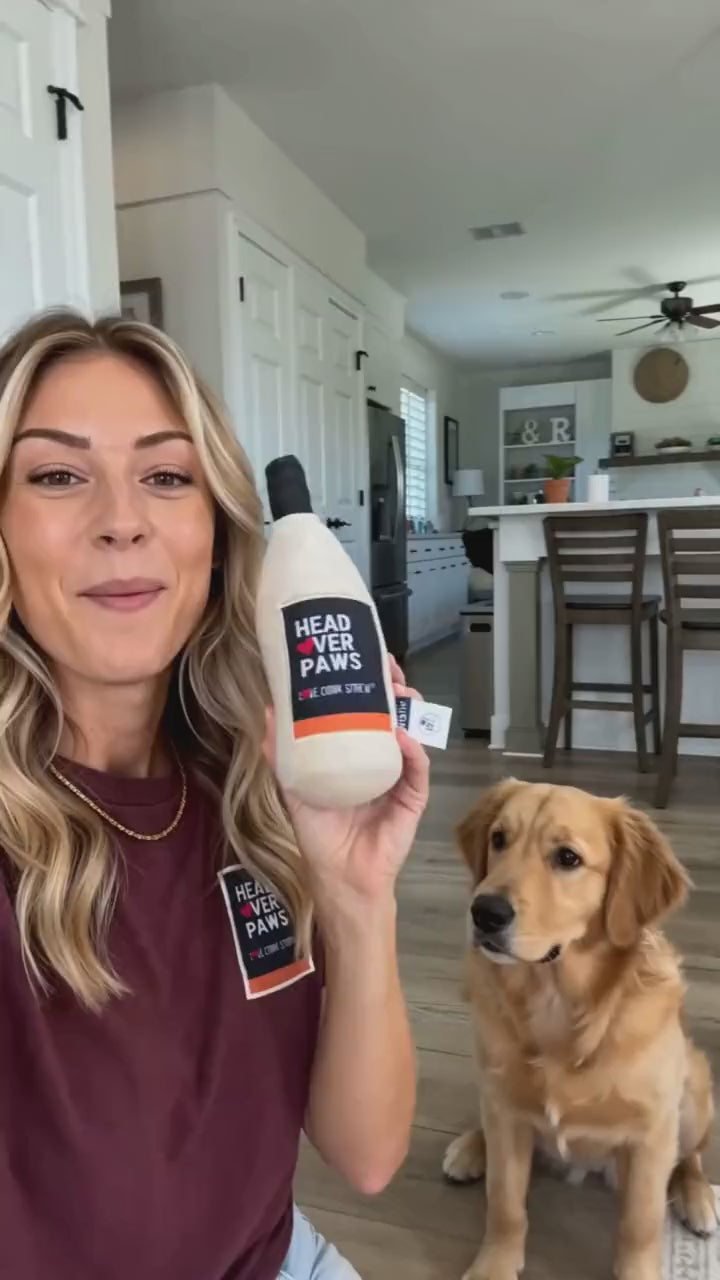 Golden retriever playing fetch with the Head Over Paws wine-bottle pup toy