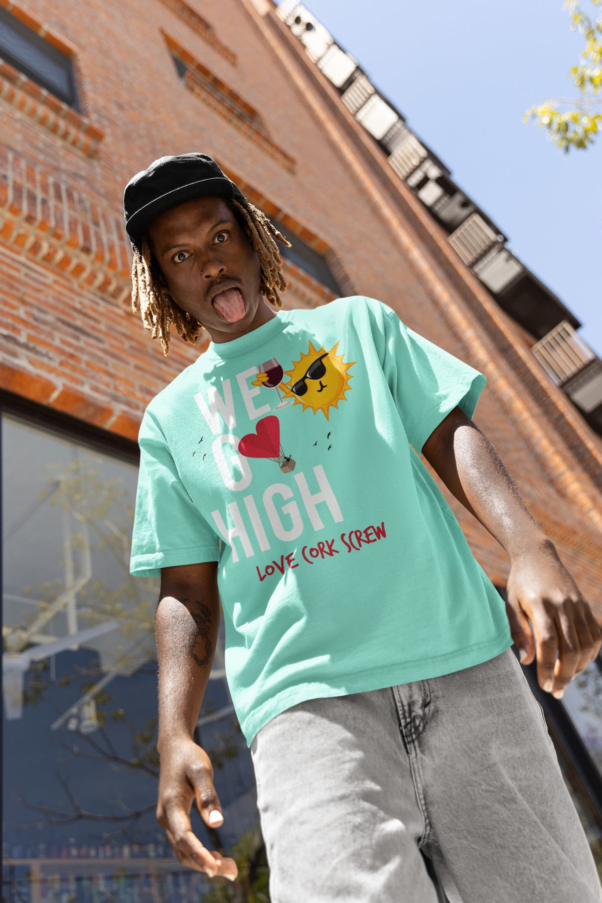 Man in the mint We Go High tee by Love Cork Screw outside a brick building